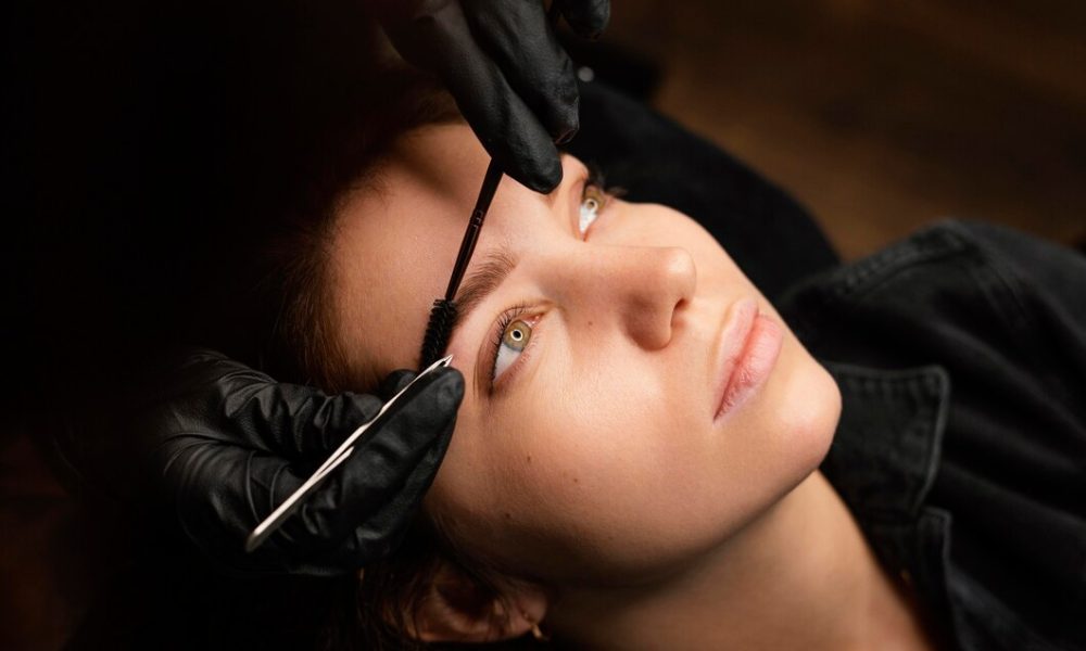 high-angle-female-clinician-doing-eyebrow-treatment-female-customer_23-2148846015